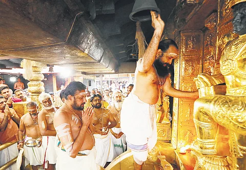 Melsanthi Mahesh Namboothiri opens the sreekovil of the hill shrine at Sabarimala on Wednesday in the presence of thantri Kandararu Brahmadathan