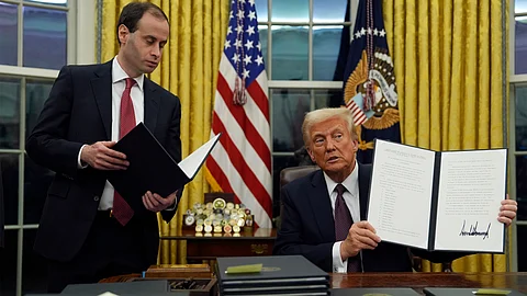 President Donald Trump holds up an executive order commuting sentences for people convicted of Jan. 6 offenses in the Oval Office of the White House, Monday.