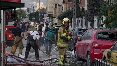 Firefighters and people clean up the scene of an explosion at a residence compound after Israeli attacks in Tehran, Friday, June 13, 2025.