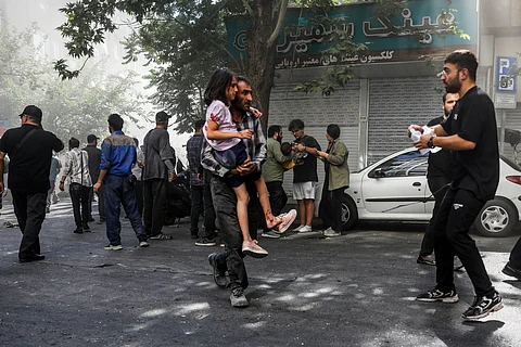 A man carries a wounded girl after an explosion in downtown Tehran amid Israel's three-day campaign of strikes against Iran, Sunday, June 15, 2025.
