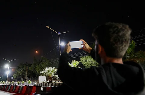 A Syrian man takes pictures with his mobile phone of Iranian missiles on their way toward Israel, as they pass over Damascus airspace, Syria, Friday, June 13, 2025.