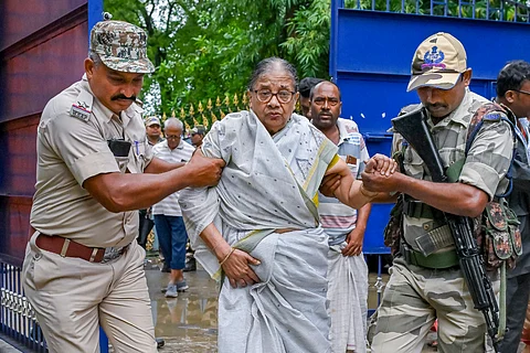 Paramilitary forces personnel assist a voter at a polling station during the by-election to the Kaliganj assembly seat, in Nadia district, Thursday, June 19, 2025.