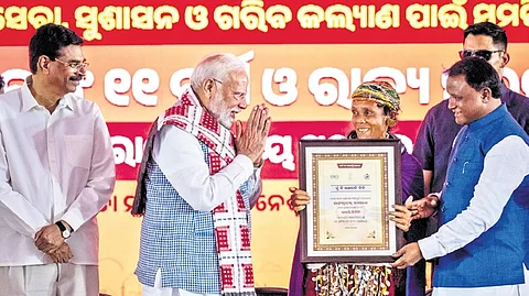 PM Narendra Modi gives a Lakhpati Didi appreciation letter to a tribal woman. Guv Hari Babu Kambhampati & CM Mohan Charan Majhi also present.
