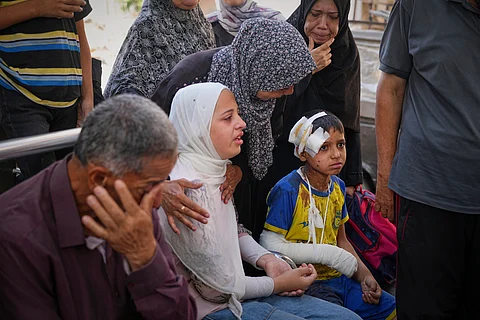 Hamam Al-Farani sits next to his sister, in white, along with other family members as the body of their father Alaa, killed in an Israeli army strike that also injured the boy, is prepared for burial at Shifa hospital in Gaza City, on Tuesday, June 24, 2025.