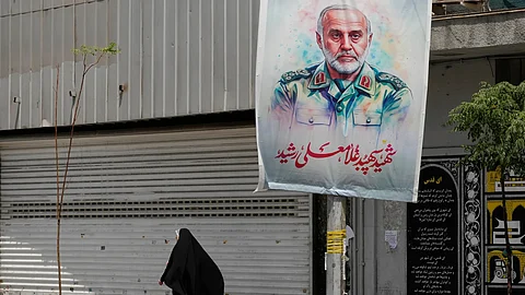 An Iranian woman walks past a banner showing head of the paramilitary Revolutionary Guard's Khatam al-Anbiya Central Headquarters Gen. Gholam Ali Rashid, who was killed in Israeli strike, at Enqelab-e-Eslami (Islamic Revolution) street in downtown Tehran, Iran, Tuesday, June 24, 2025