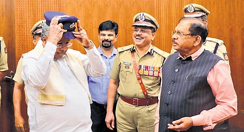 Chief Minister Siddaramaiah tries a police cap at the DG Office in Bengaluru on Friday. Home Minister Dr G Parameshwara, DG & IG MA Saleem and others look on