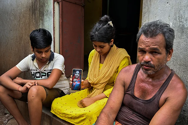 Santosh Bal (right) with his son Rohit and daughter Lopamudra, who is showing her mother's photo.