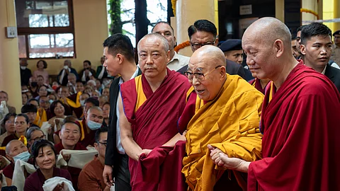 Tibetan spiritual leader the Dalai Lama, in yellow robe, is helped by attendant monks as he arrives to preside over an event during which Tibetan exiles prayed for his longevity, a day before his 90th birthday, in Dharamshala, India, Saturday, July 5, 2025.