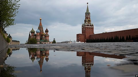 The Kremlin's Spasskaya Tower, center, and St. Basil's Cathedral, left, reflected in rainwater puddles in an empty Red Square during the evening rush hour in Moscow, Russia, May 7, 2020. (AP via VOA)