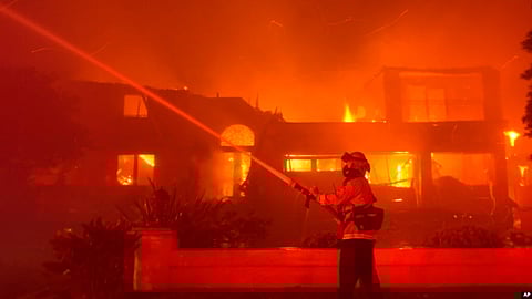 A firefighter works to put out a building burning during a wildfire on May 11, 2022, in Laguna Niguel, Calif. (AP via VOA)