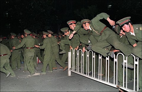 People Liberation Army (PLA) soldiers leap over a barrier on Tiananmen Square in central Beijing on June 4, 1989 during heavy clashes with people and dissident students. (RFA)