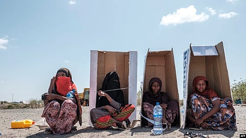 Women sit under UNHCR-branded cardboard boxes as they wait to be registered by the authorities at the compound of the Agda Hotel, in the city of Semera, Afar region, Ethiopia, Feb. 14, 2022.