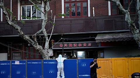 A person in a protective suit looks over barricades set around a sealed-off area, during a lockdown to curb the spread of the coronavirus disease (COVID-19) in Shanghai, China, April 11, 2022.