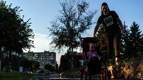 A mother pushes her child in a carriage through a puddle after a rainstorm in Pokrovsk, Donetsk region, eastern Ukraine, Aug. 4, 2022.