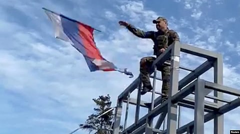 A Ukrainian soldier takes down a Russian flag hoisted on a monument in Lyman on October 1.