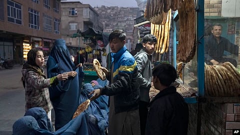 A man distributes bread to women outside a bakery in Kabul, Afghanistan.