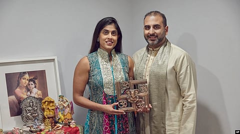 Sheetal Deo and her husband, Sanmeet Deo, hold a Hindu swastika symbol in their home in Syosset, N.Y., Nov. 13, 2022.