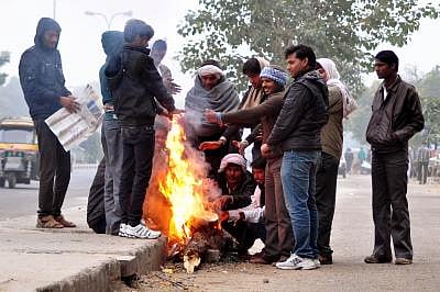 Jaipur: People warm themselves around a fire on a cold winter morning in Jaipur on Dec 14, 2014. (Photo: Ravi Shankar Vyas/IANS)