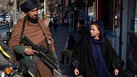 FILE - A Taliban fighter stands guard as a woman walks past in Kabul, Afghanistan, Dec. 26, 2022. (VOA)