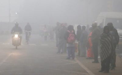 New Delhi: People stand on a road waiting for a bus as the thick layer of fog engulfs on a cold morning, in New Delhi on Monday, Jan. 09, 2023. (Photo: Wasim Sarvar/IANS)