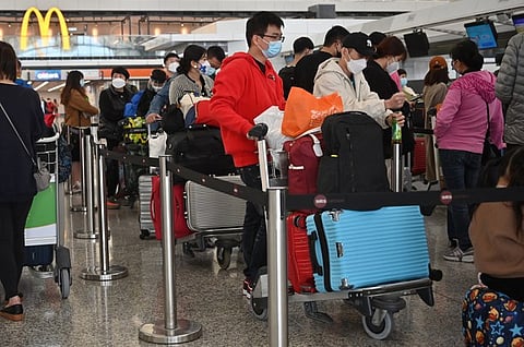 Passengers queue to check-in at the international airport in Hong Kong on Dec. 28, 2022. (AFP)