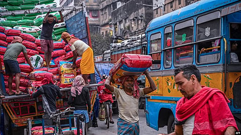 Laborers unload sealed sacks of spices at a wholesale market in Kolkata on Feb. 1, 2023. (AFP)
