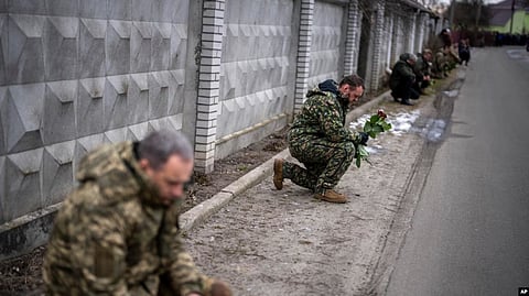 Ukrainian soldiers kneel as they await the coffin of Oleksandr Maksymenko to pass by during his funeral in his home-village Kniazhychi, Feb. 13, 2023. Oleksandr, a civilian who was a volunteer in the armed forces of Ukraine, was killed in the fighting in Bakhmut area.