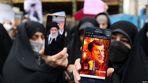 FILE - A protester shows a cartoon of French President Emmanuel Macron during a protest condemning the French magazine Charlie Hebdo for republishing cartoons insulting Iran's Supreme Leader Ayatollah Ali Khamenei, in Tehran, Iran, Jan. 11, 2023. (Reuters)