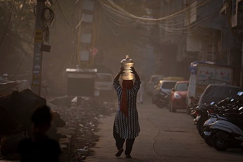 A woman carries a water can from a mobile water tanker in a residential area in New Delhi, India, on March 22, 2023. (AP)