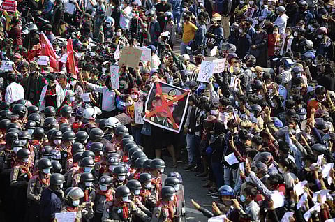 In this Feb. 8, 2021 photo, Myanmar anti-coup protesters display a defaced image of Myanmar junta leader Senior General Min Aung Hlaing as they face off with riot police in Naypyidaw, Myanmar.