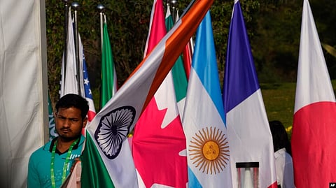 A worker carries Indian national flag to place it with those of other participating countries at the opening session of the G20 foreign ministers meeting, in New Delhi, India, March 2, 2023. (VOA)