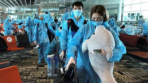 A Vietnamese woman carries a stuffed animal while boarding a repatriation flight from Singapore to Vietnam at Changi airport, Singapore, Aug 7, 2020.