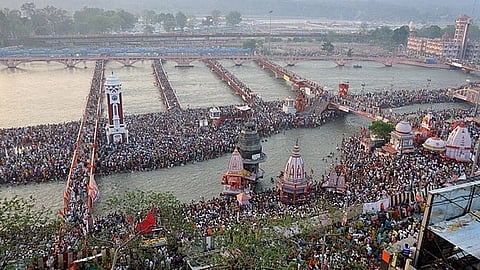 Maha Kumbh 2025 is written in bold at the top of the hoarding. It is followed by a description that says 'The World's Largest Spiritual Gathering'. (Wikimedia)