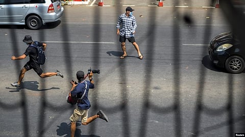 FILE - Pro-democracy protesters and a journalist run as riot police officers advance during a rally against the military coup in Yangon, Myanmar, Feb. 27, 2021.