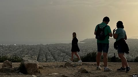 Tourists visit the Filopappou Hill, as Greece is hit by high temperatures and Saharan dust due to southern winds, in Athens, Greece, April 2, 2024. VOA