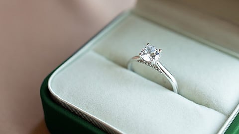 A silver engagement ring with a sparkling diamond displayed in a cushioned jewelry box.