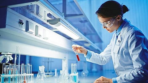 Scientist in a lab coat examining a test tube with red liquid