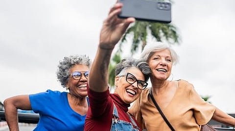 Three elderly women smiling and taking a selfie together