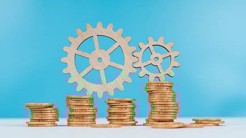 Wooden gears and coin stacks symbolizing financial growth and teamwork.