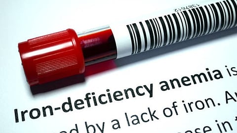 Blood sample tube placed over text about iron-deficiency anemia.