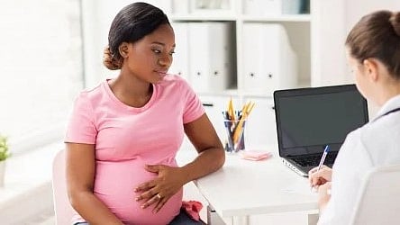 Pregnant woman talking to a doctor in an office.