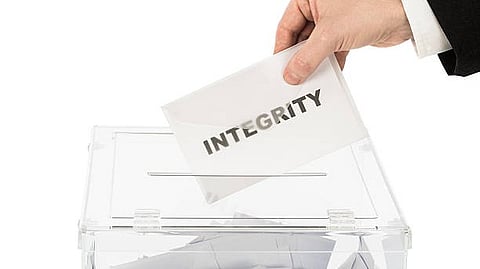 “Person placing an envelope labeled ‘INTEGRITY’ into a box