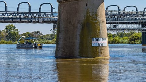 Bridge pillar with a flood level mark over a river.”