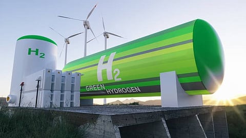 Green hydrogen storage tanks with wind turbines in the background