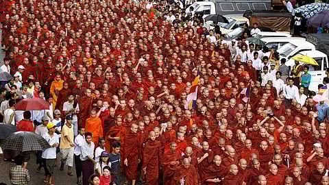 Large group of monks in orange robes gathered for a ceremony.