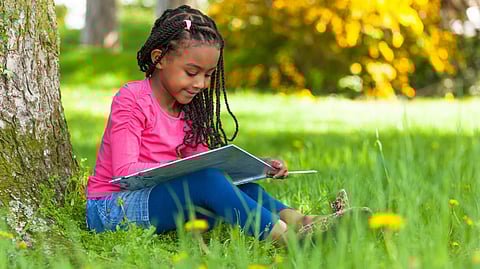 A child sits in front of a computer screen, reading a digital book with concentration and interest.