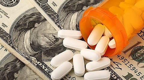 Orange pill bottle with white tablets spilled over US dollar bills.