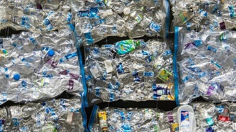 Compressed stacks of crushed plastic bottles ready for recycling.