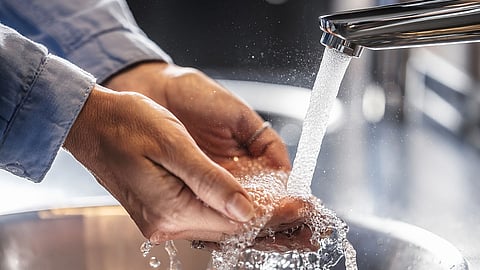 A person washing their hands under running water at a sink, emphasizing hygiene and cleanliness.