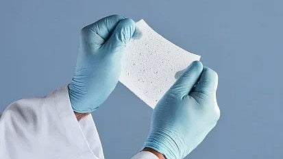 A person in gloves holds a piece of paper, focusing on the document's details.